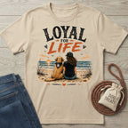Beige crewneck t-shirt featuring a graphic of a woman and dog sitting on a beach at sunset with Loyal For Life text.