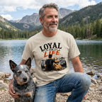 Man wearing a beige crewneck t-shirt with a Loyal For Life graphic of a man and dog overlooking mountains by a lake.
