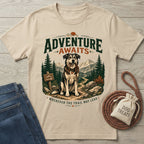 Beige cotton t-shirt featuring a graphic of a dog holding a leash on a mountain trail with Adventure Awaits text.