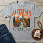 Grey crewneck t-shirt featuring a mountain, river, and dog graphic with the text Autumn Adventures.