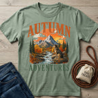 Sage green crewneck t-shirt featuring a graphic of a dog sitting by a mountain stream during autumn.