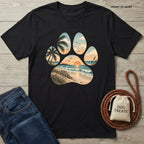 Black cotton t-shirt featuring a paw print graphic filled with a beach sunset, ocean waves, and palm trees.
