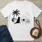 White crew neck t-shirt featuring a black graphic of a dog sitting on a beach under a palm tree at sunset.