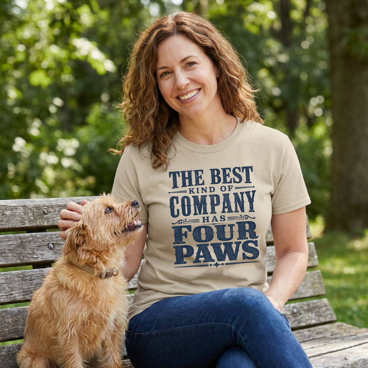 Woman wearing a beige crewneck t-shirt with vintage navy blue text that reads The Best Kind of Company Has Four Paws.