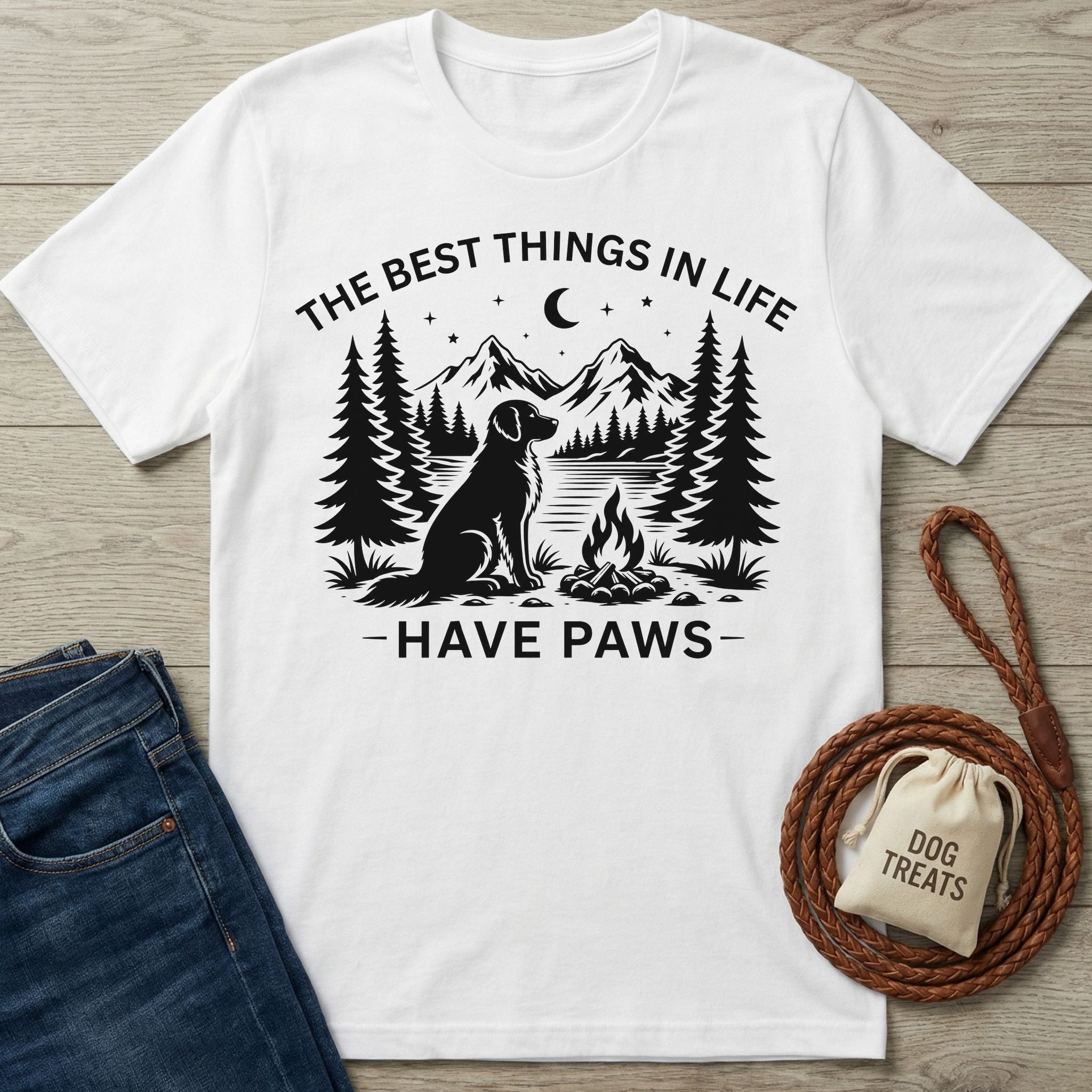 White cotton t-shirt featuring a black graphic of a dog by a campfire, mountains, and the text The Best Things In Life Have Paws.