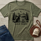 Olive green crewneck t-shirt featuring a black graphic of a dog, campfire, and mountains with the text The Best Things In Life Have Paws.