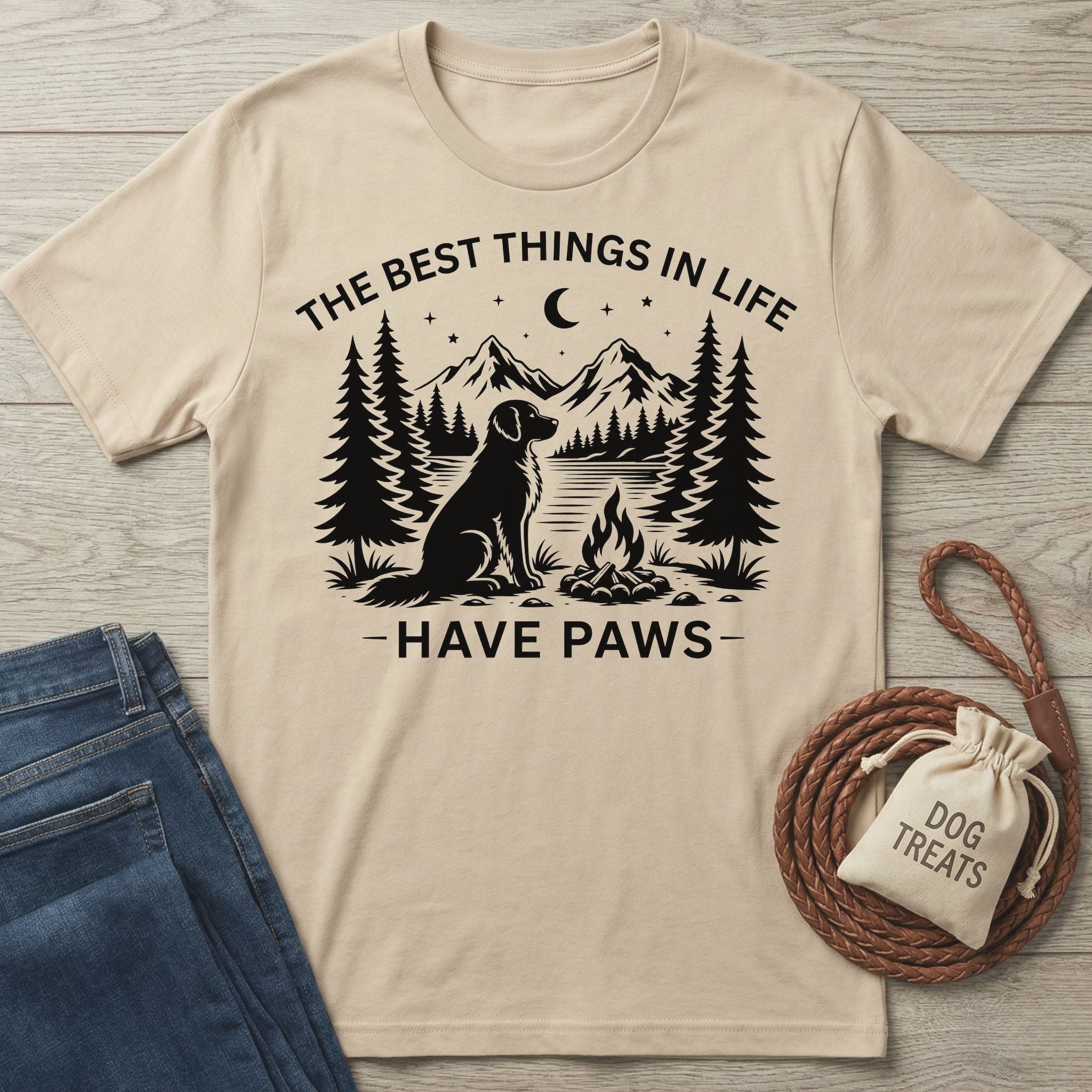 Beige crewneck t-shirt featuring a black graphic of a dog by a campfire, mountains, and the text The Best Things In Life Have Paws.