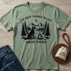 Sage green crewneck t-shirt featuring a black graphic of a dog, campfire, mountains, and the text The Best Things In Life Have Paws.