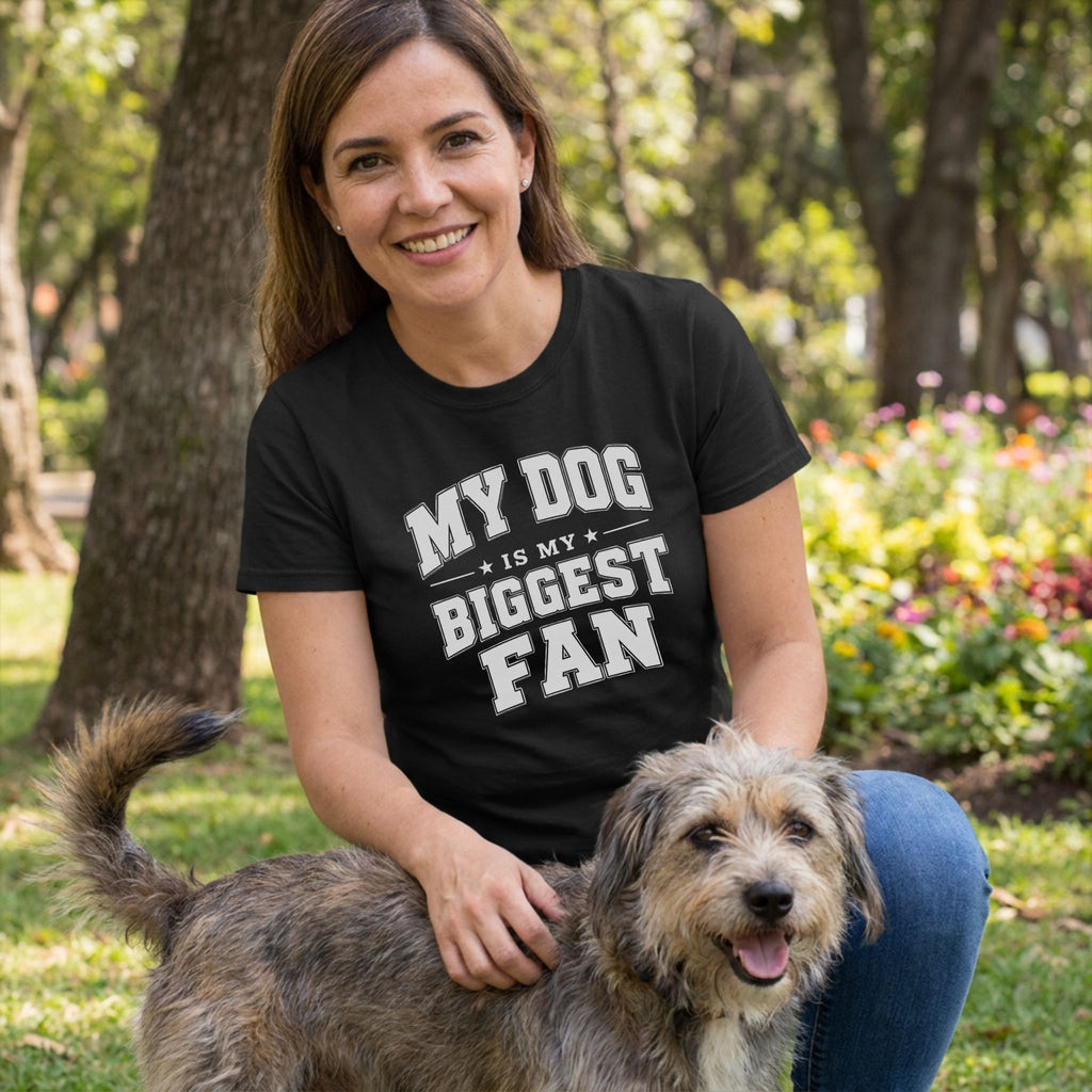 Woman wearing a black crew neck t-shirt with white text reading My Dog Is My Biggest Fan while petting a scruffy dog outdoors.