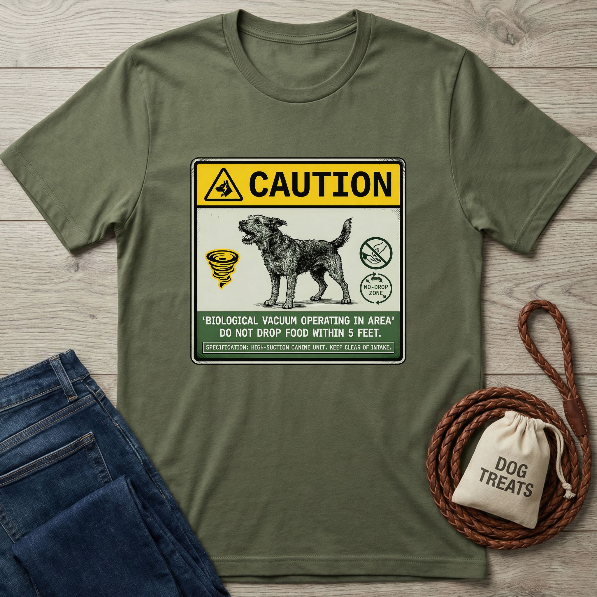 Olive green Gildan Softstyle t-shirt with a "Caution: Biological Vacuum" dog graphic, beside jeans and dog treats.