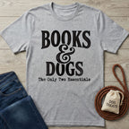 Grey crewneck T-shirt with black Books & Dogs graphic text on a wooden background with jeans and a dog treat bag.