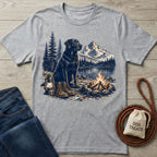 Grey crewneck t-shirt featuring a graphic of a black dog, campfire, mountains, and hiking boots by a lake.
