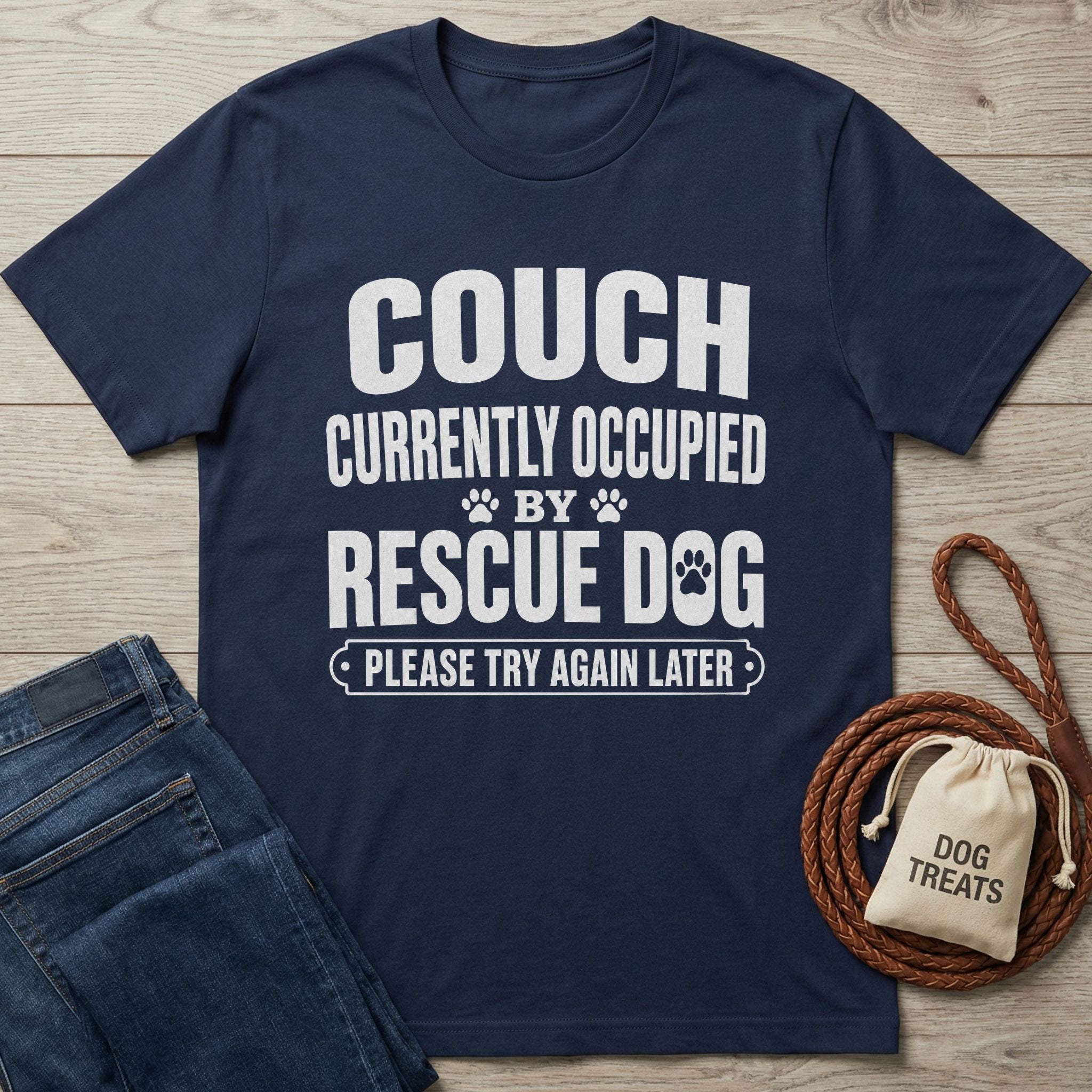 Woman in a navy "Couch Occupied" tee petting a rescue dog by a lake at sunset.