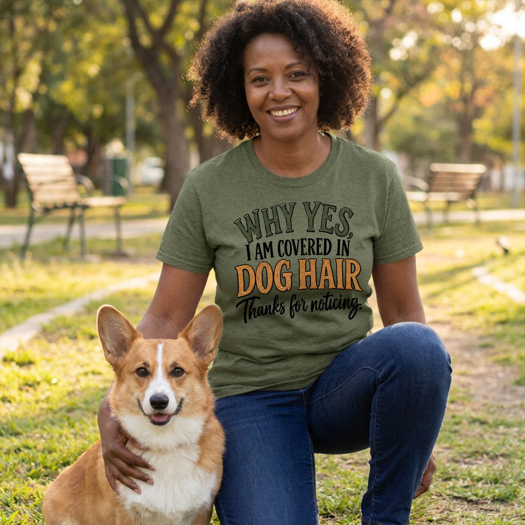 Woman wearing an olive green T-shirt with the text Why Yes, I Am Covered In Dog Hair, kneeling outdoors with a Corgi.