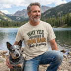 Beige crewneck T-shirt with the text Why Yes, I Am Covered In Dog Hair worn by a man beside a dog at a lake.