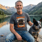 Man wearing a charcoal grey t-shirt with a Creepin It Canine Dachshund Halloween graphic, sitting by a mountain lake.