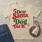 Beige crewneck t-shirt with festive red, green, and gold Dear Santa, The Dog Did It text and a Santa hat graphic.