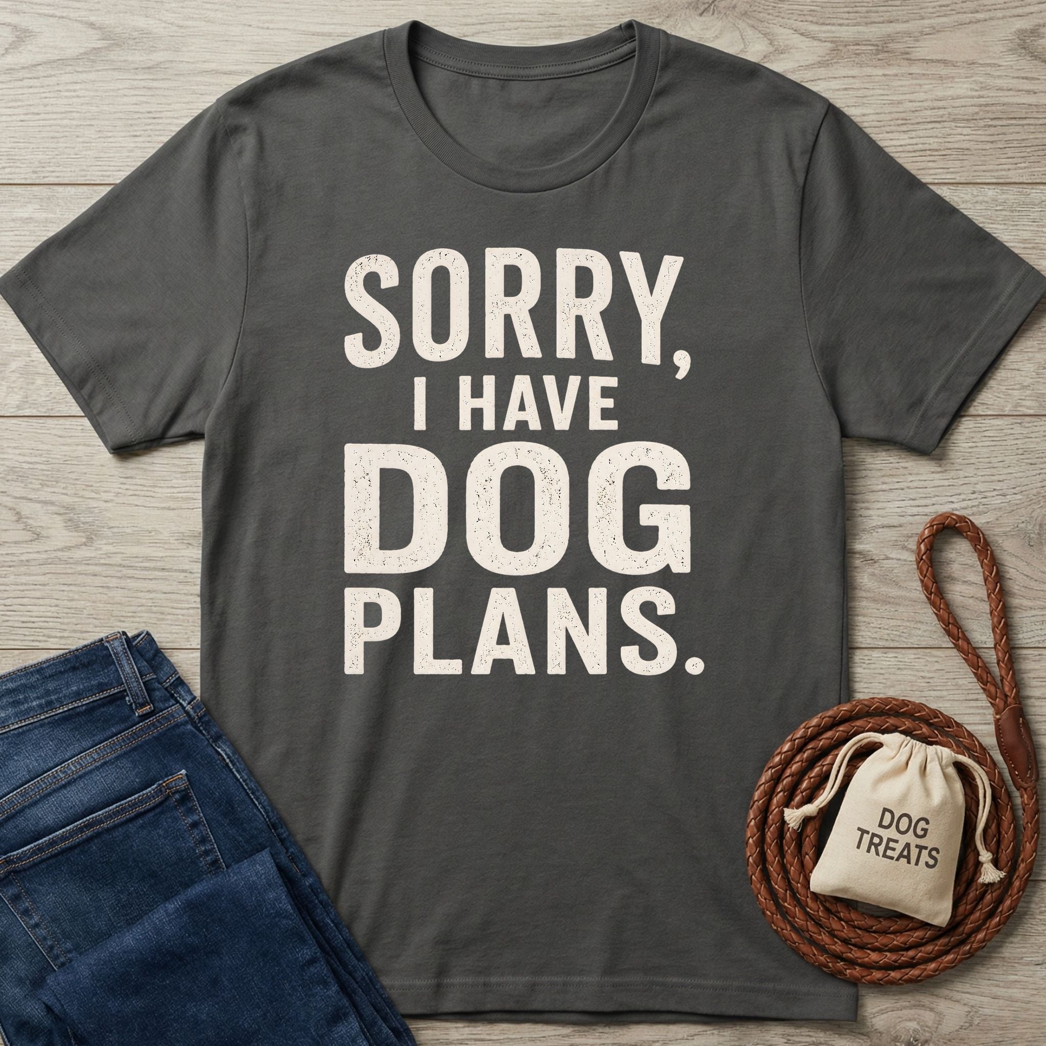 Charcoal gray crewneck T-shirt featuring the white text Sorry, I Have Dog Plans, laid on a wooden surface with jeans and a leash.