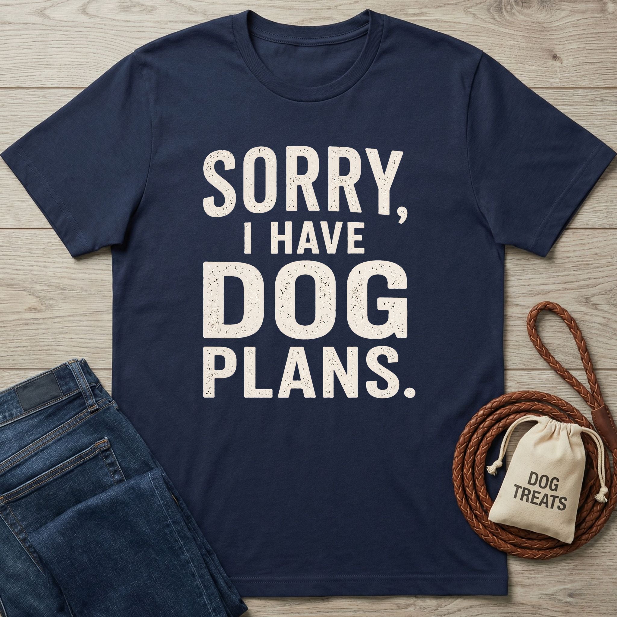 Navy blue crewneck t-shirt with distressed white text reading Sorry, I Have Dog Plans, laid on a wooden background.