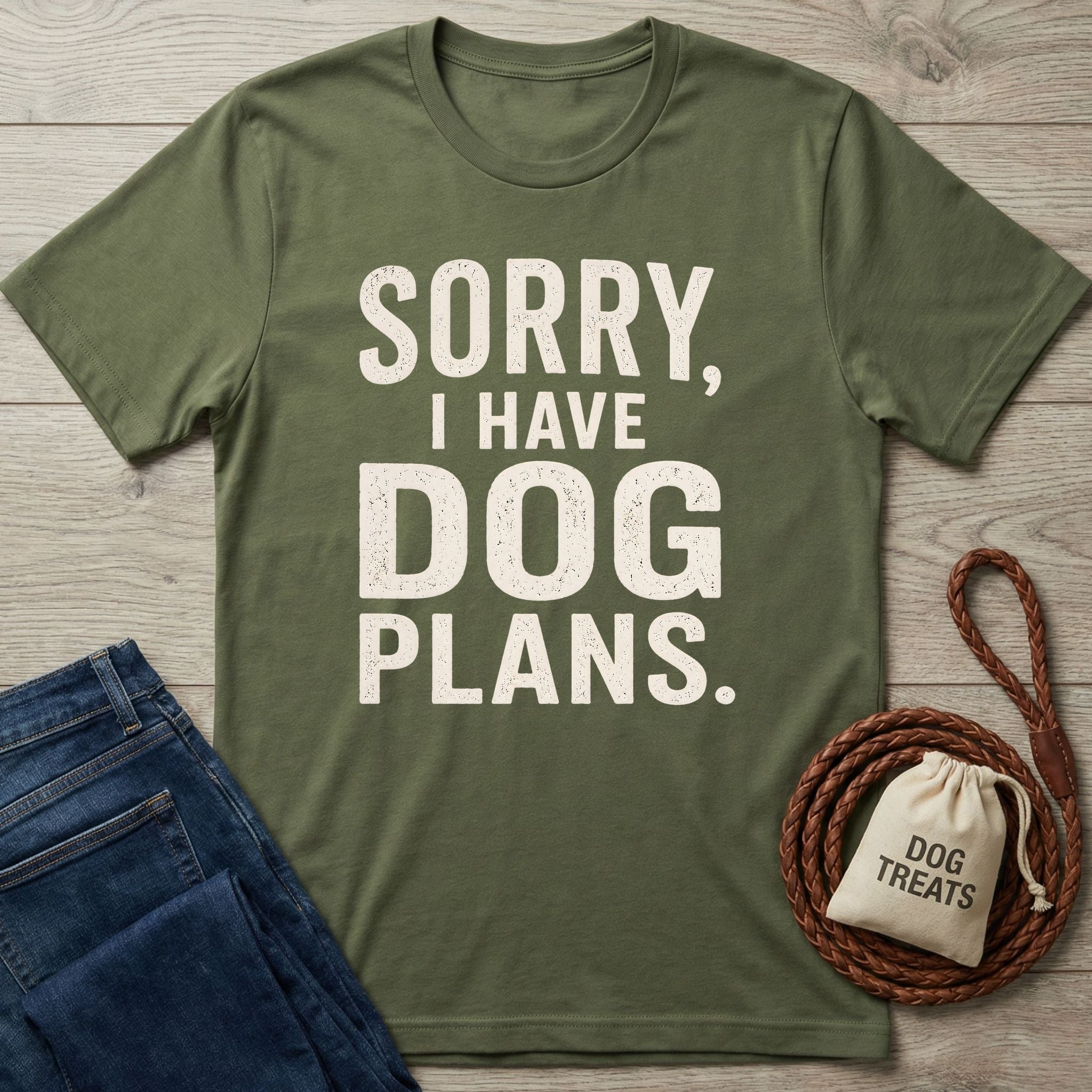 Olive green cotton t-shirt with Sorry, I Have Dog Plans text, displayed with a brown leather leash and dog treat bag.