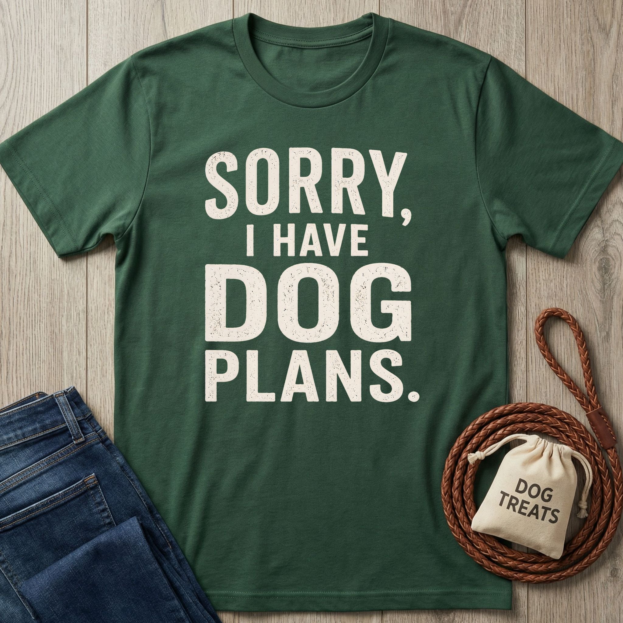 Forest green crewneck t-shirt with white distressed text reading Sorry, I Have Dog Plans, styled with a leash and treat bag.