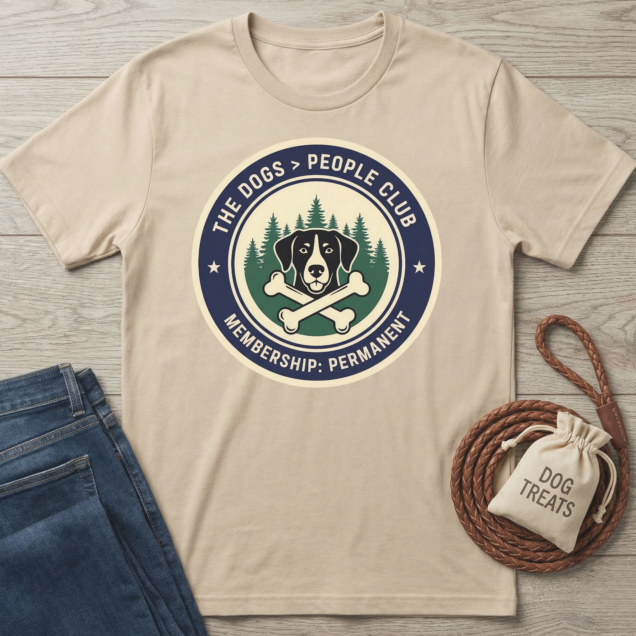 Beige Gildan Softstyle® t-shirt with "The Dogs > People Club" graphic, blue jeans, and dog treats bag.