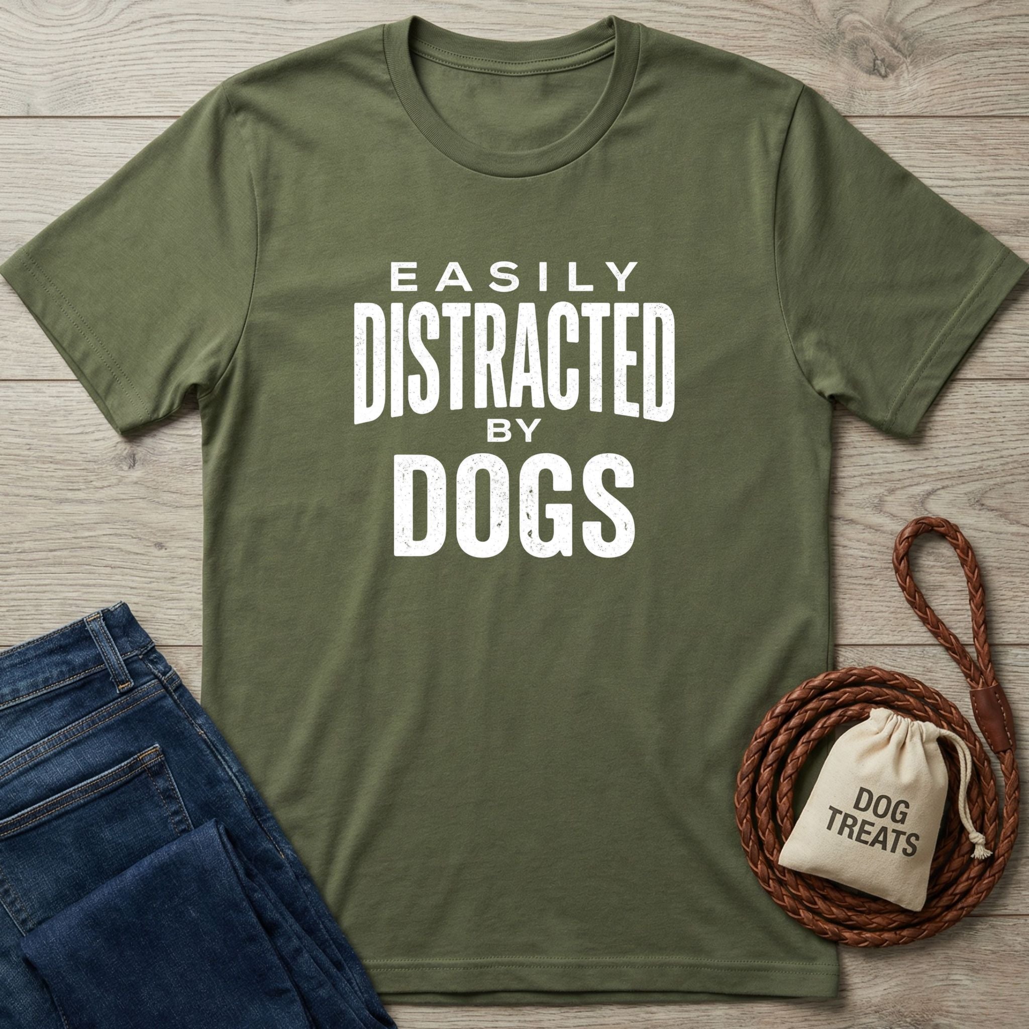 Olive green Gildan Softstyle® t-shirt with "Easily Distracted By Dogs" in white text, next to jeans and dog treats.