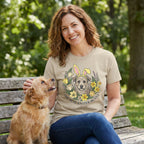 Woman in a tan "The Real Easter Bunny" t-shirt with a dog in a floral wreath, petting a small brown dog on a park bench.