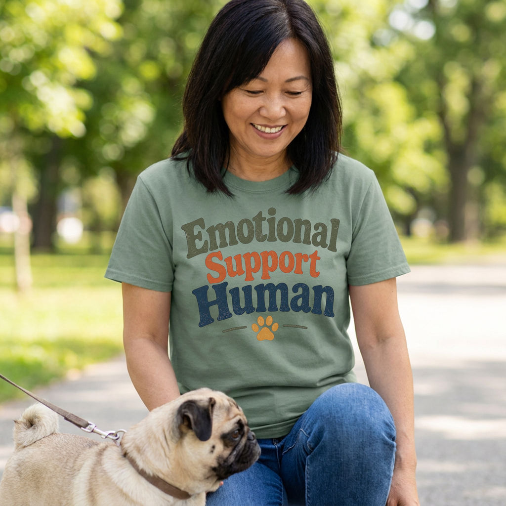 Woman in a sage green "Emotional Support Human" t-shirt with a pug dog.