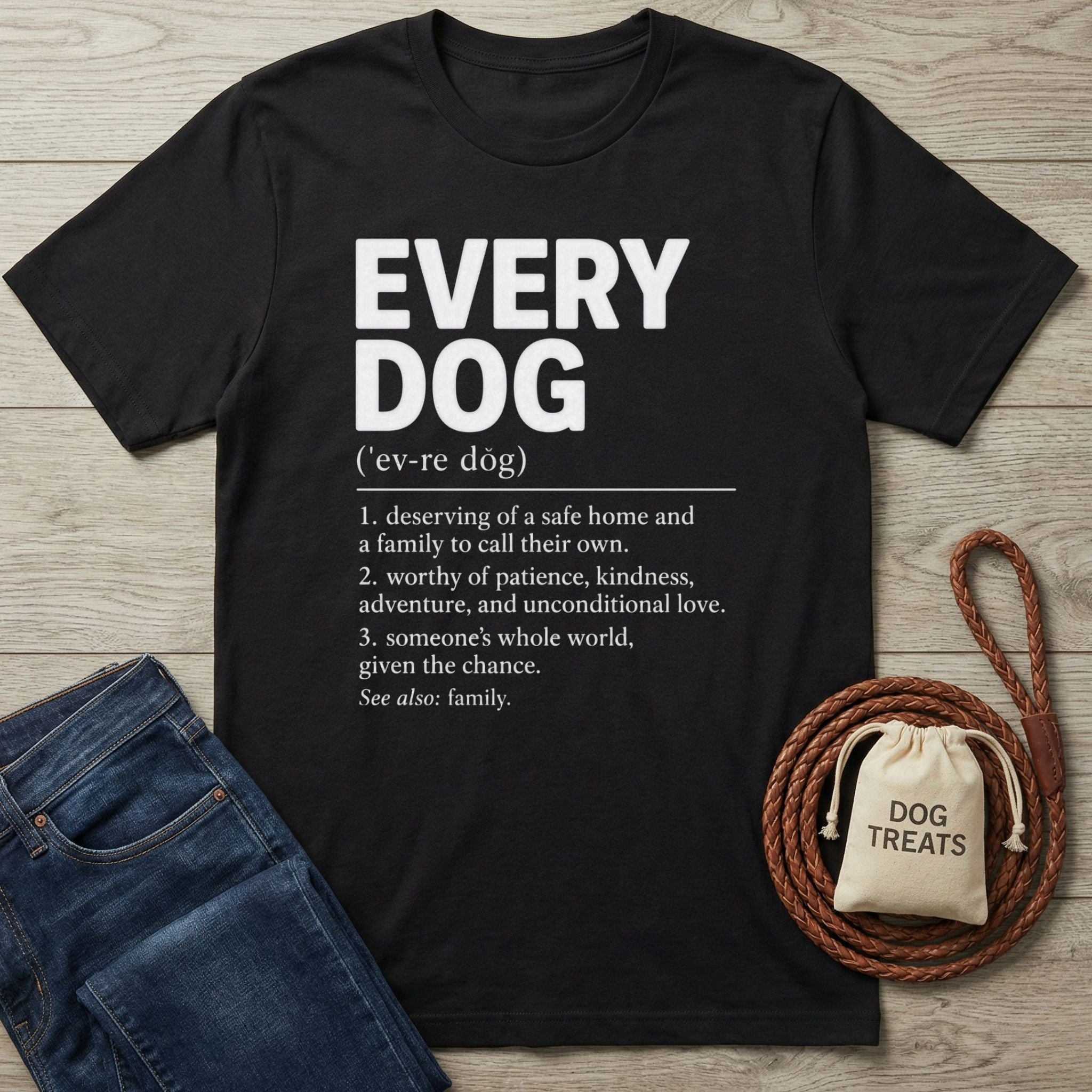 Black cotton t-shirt with white Every Dog definition graphic, displayed with blue jeans, a leather leash, and a treat bag.