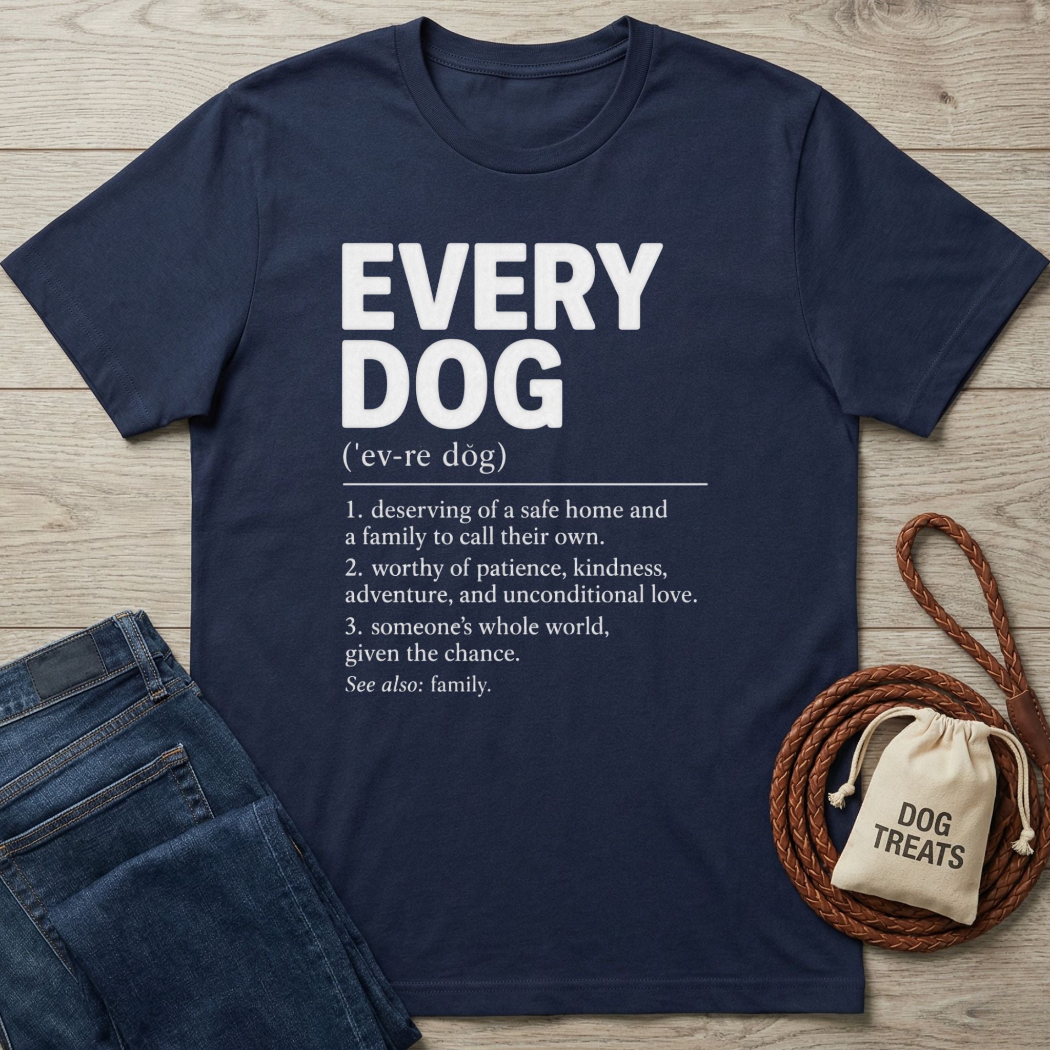 Navy blue cotton t-shirt featuring a white dictionary-style definition of Every Dog, laid on a wooden surface with dog accessories.