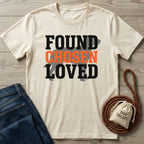 Cream Gildan Softstyle® t-shirt with "FOUND CHOSEN LOVED" text, dark jeans, and dog treats bag.