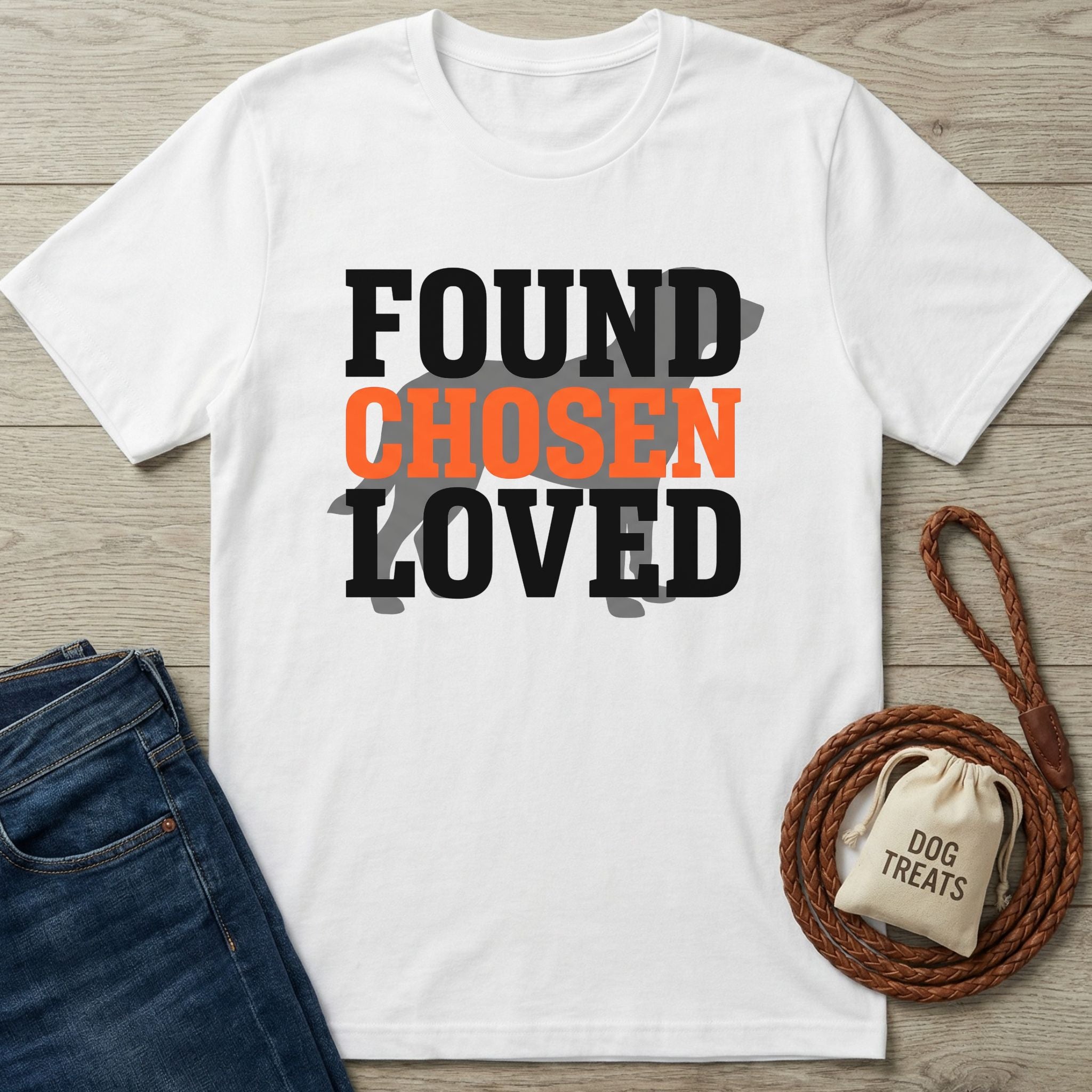 White Gildan Softstyle t-shirt with "FOUND CHOSEN LOVED" text and a dog silhouette, beside jeans and a leash.