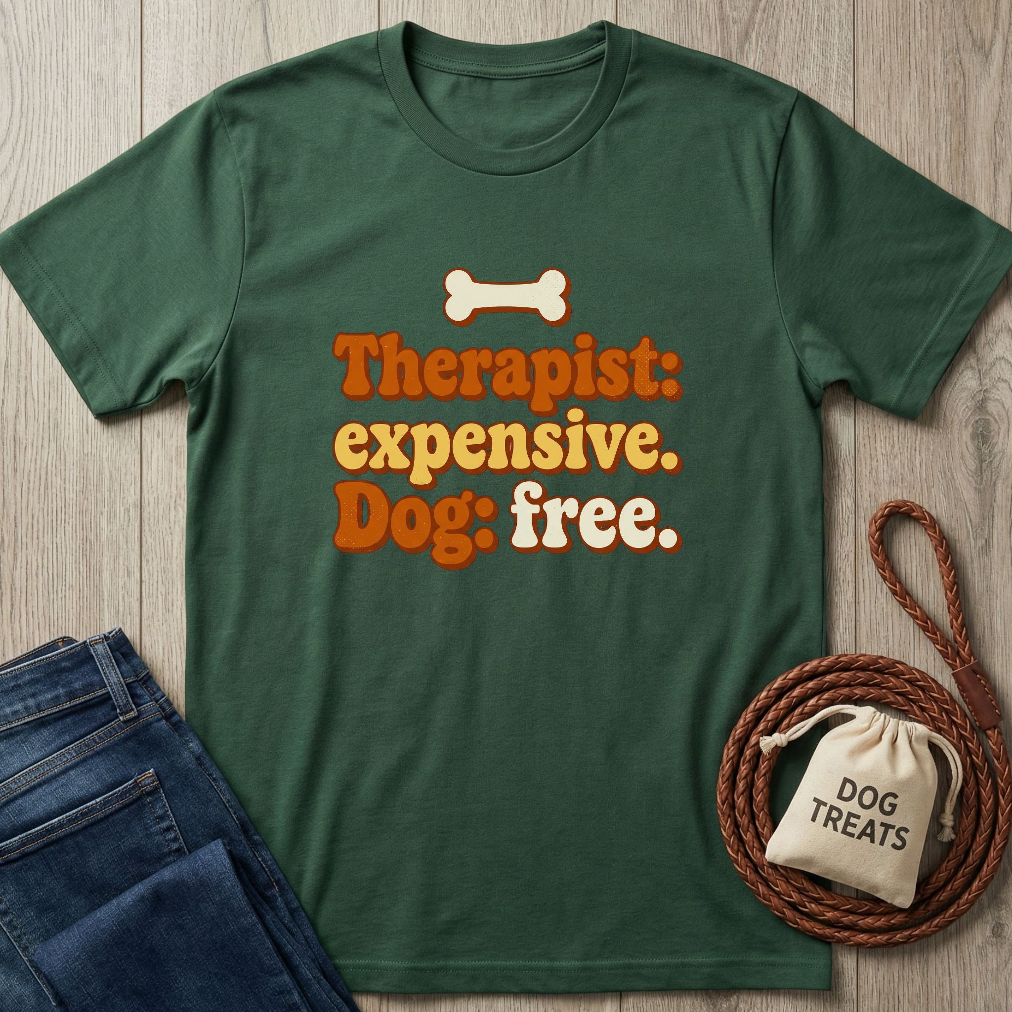 Dark green "Therapist: expensive. Dog: free." t-shirt with a bone graphic, folded jeans, and dog treats.