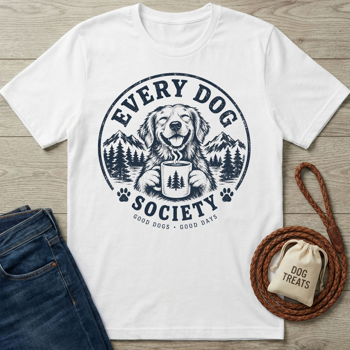 White cotton t-shirt featuring a navy graphic of a smiling dog holding a coffee mug with mountain and forest scenery.