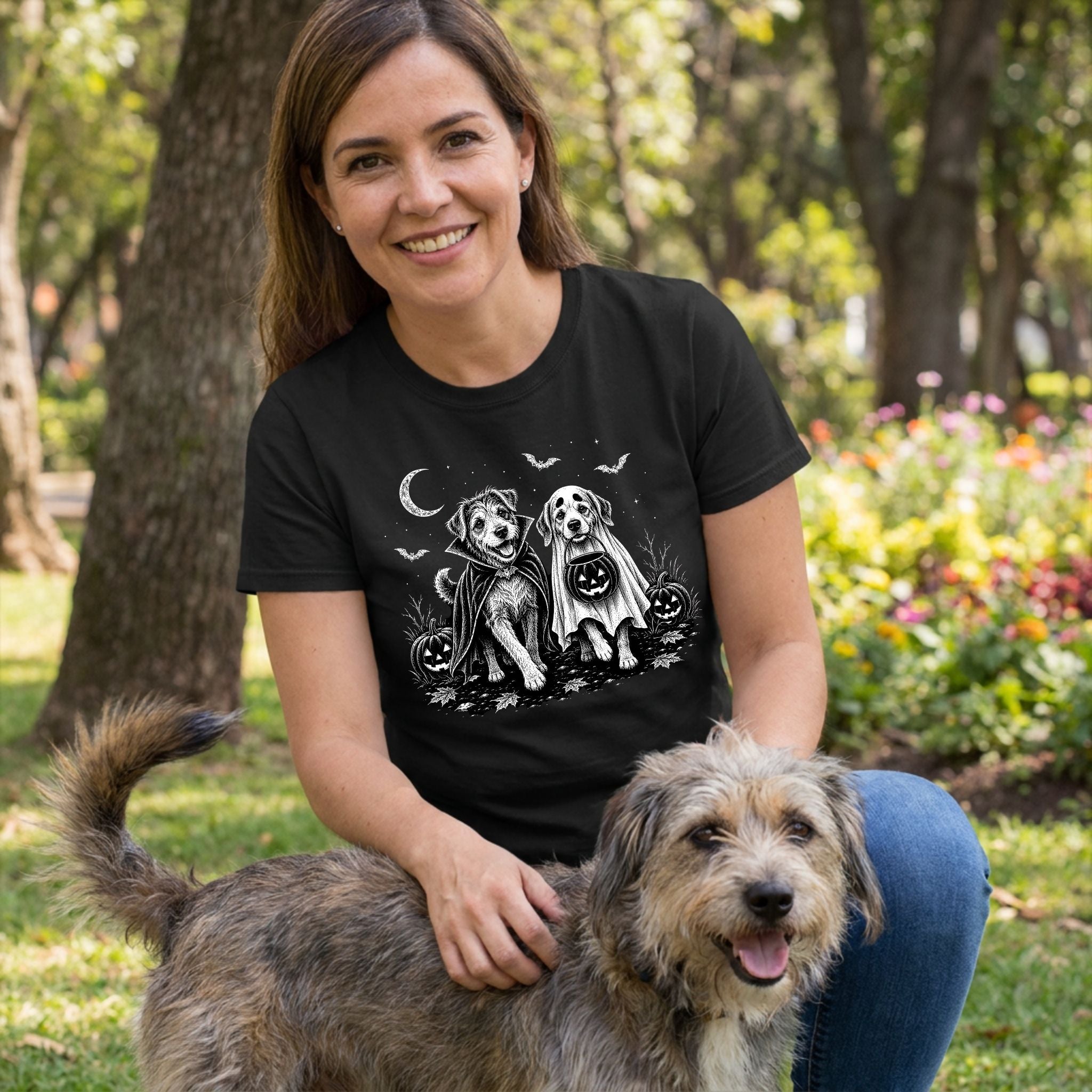 Woman wearing a black crewneck t-shirt featuring a white graphic of two dogs in Halloween costumes under a crescent moon.