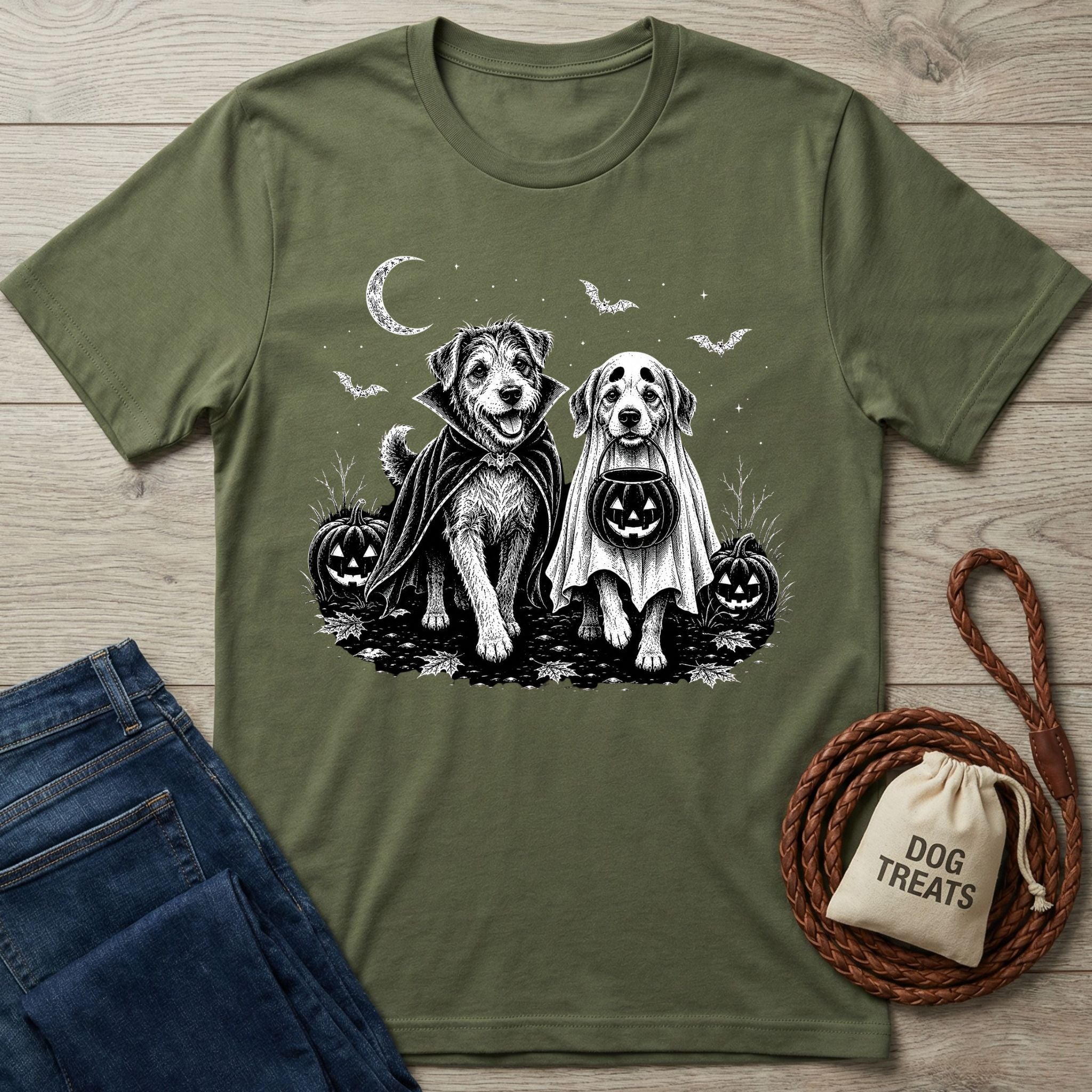 Olive green t-shirt featuring two dogs in Halloween costumes, a vampire cape and ghost sheet, under a crescent moon and bats.