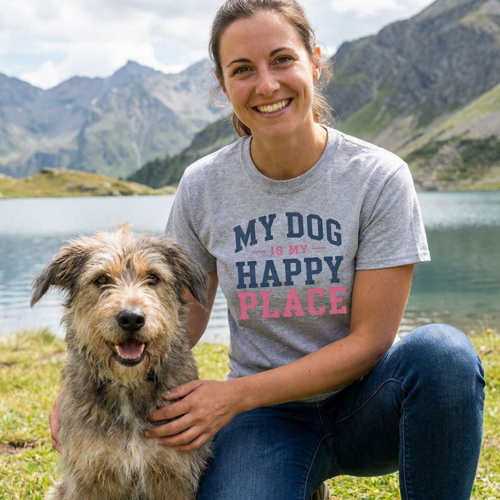 Woman wearing a grey crewneck t-shirt with My Dog Is My Happy Place text, kneeling beside a dog by a mountain lake.