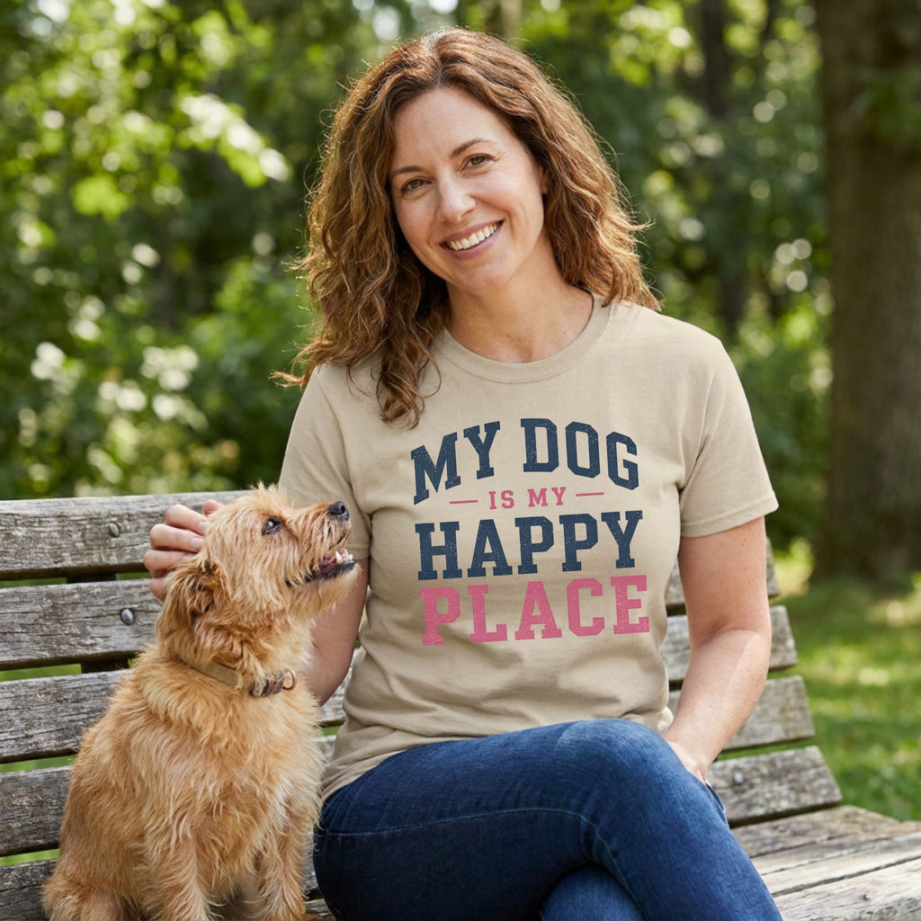 Woman wearing a tan crewneck t-shirt with My Dog Is My Happy Place text, sitting on a park bench with a small terrier.