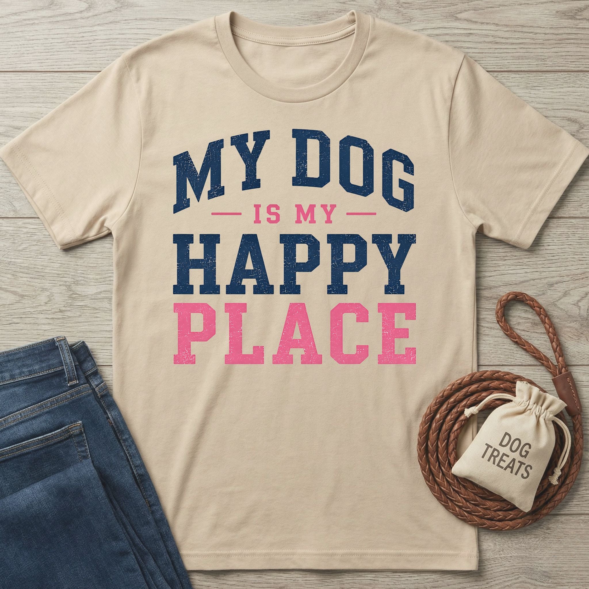 Beige crewneck t-shirt with navy and pink distressed text reading My Dog Is My Happy Place, laid on a wooden surface.