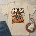 Beige crewneck t-shirt featuring a rockstar dog in a skeleton costume, sunglasses, and cap with Here For The Bones text.