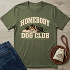 Olive green cotton t-shirt featuring a sleeping dog graphic with Homebody Dog Club text, laid on a wooden surface.