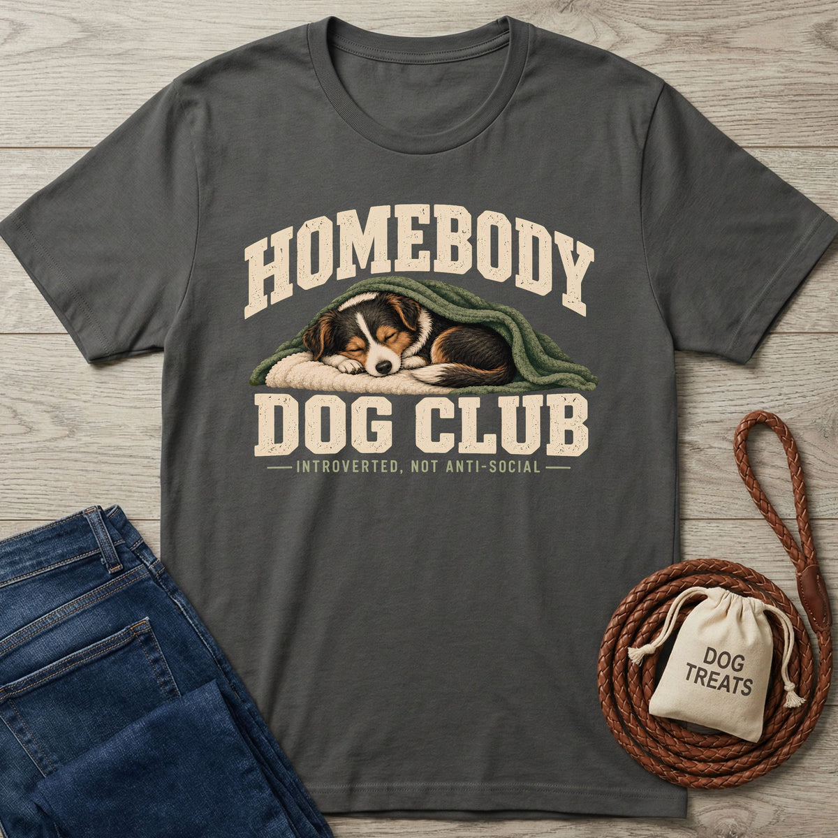 Charcoal gray graphic t-shirt featuring a sleeping dog under a blanket with Homebody Dog Club text on a wood background.
