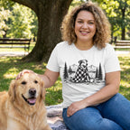 Woman wearing a white crew neck t-shirt featuring a black and white graphic of a dog in a plaid blanket by a lake.