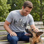 Man wearing a grey crewneck t-shirt with a graphic of a dog in a plaid blanket by a campfire, sitting on a park bench.