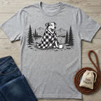 Grey crewneck t-shirt featuring a black and white illustration of a dog in a plaid blanket by a campfire with coffee.