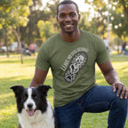 Man in olive green "Leave No Dog Behind" tee with a paw print boot graphic, kneeling beside a Border Collie.