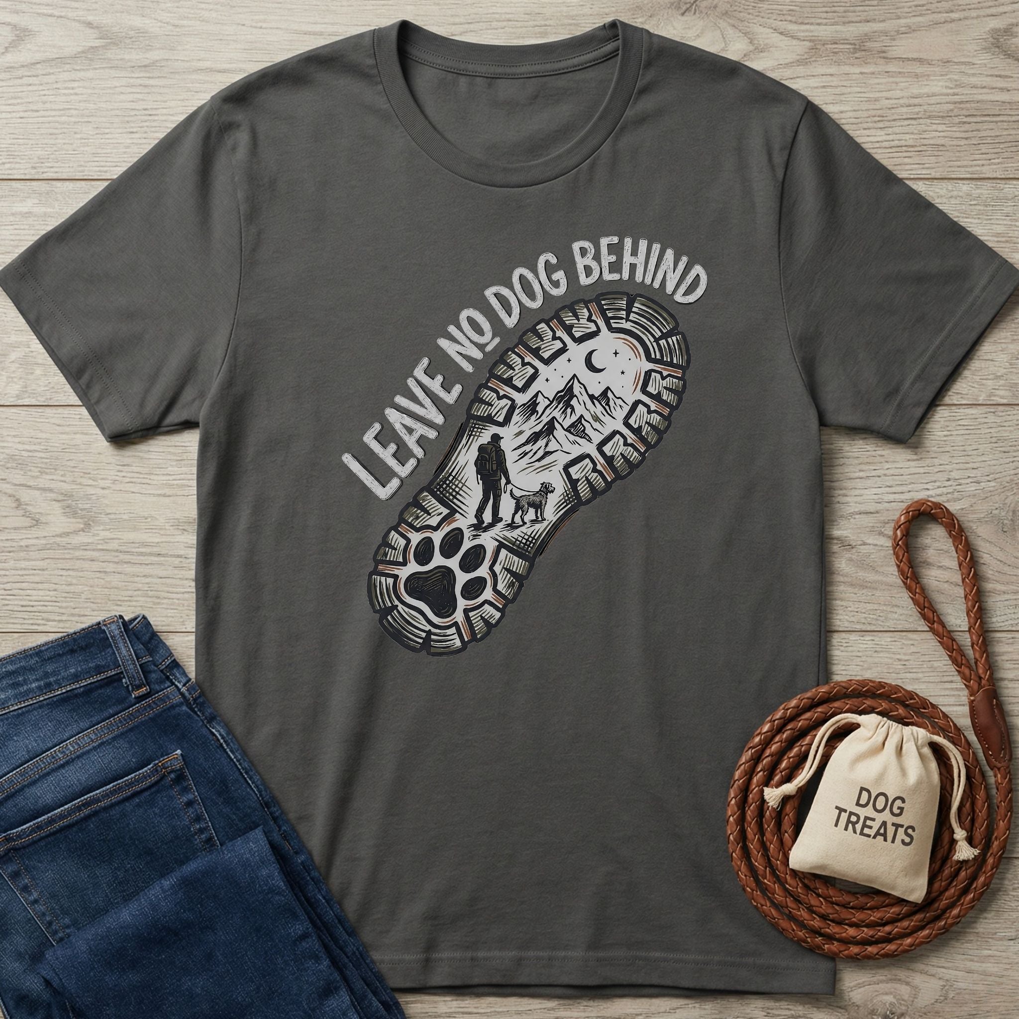 Charcoal gray Gildan Softstyle® t-shirt with "Leave No Dog Behind" boot print graphic, blue jeans, and dog treats bag.