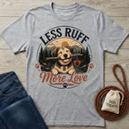 Grey t-shirt featuring a happy dog with a stick, mountain landscape, and the text Less Ruff More Love in a circular design.