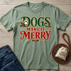 Sage green crewneck T-shirt with vintage-style Dogs Make It Merry holiday text, holly, and paw print graphics.